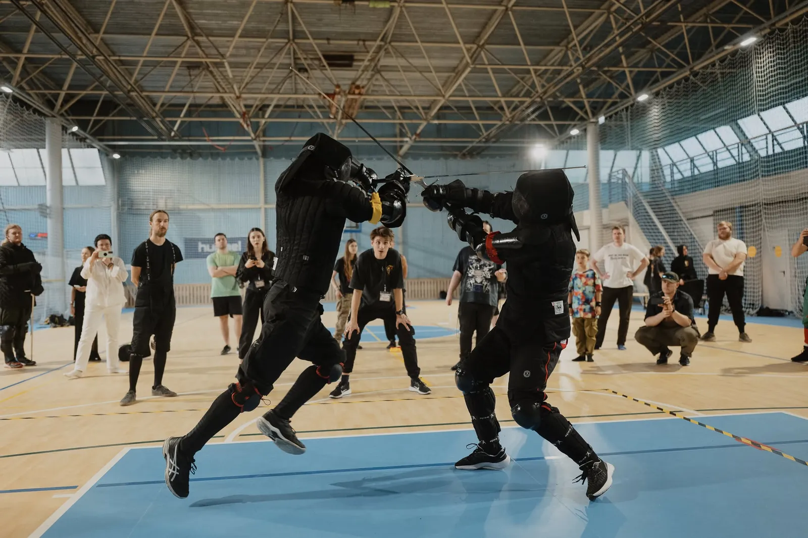 Longsword sparring in a sports hall with club members watching