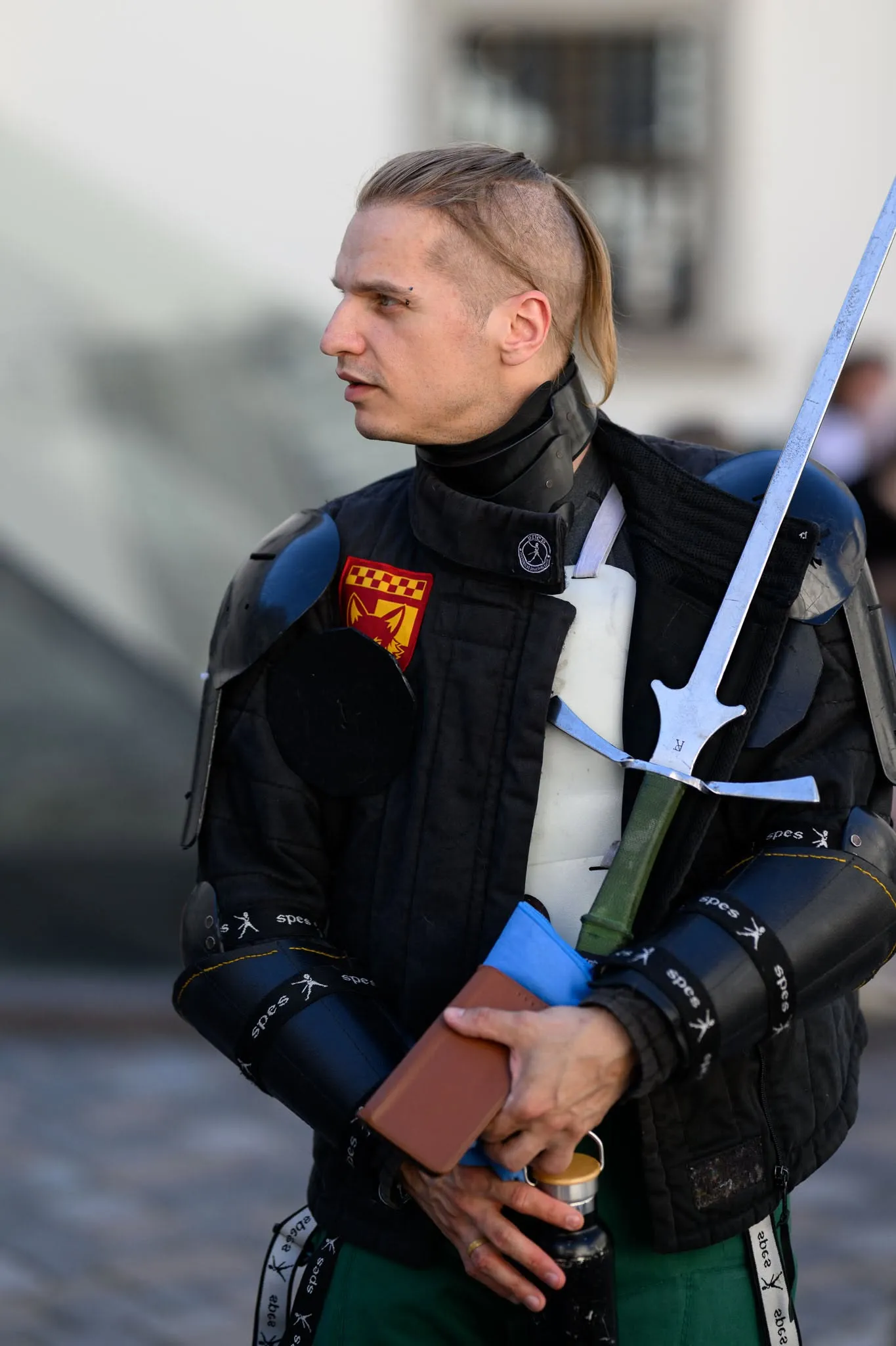 Fencer with a longsword resting on his shoulder at an outdoor event