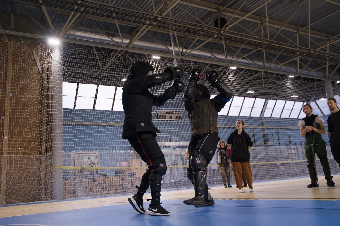Two fencers binding swords at close range in a sports hall